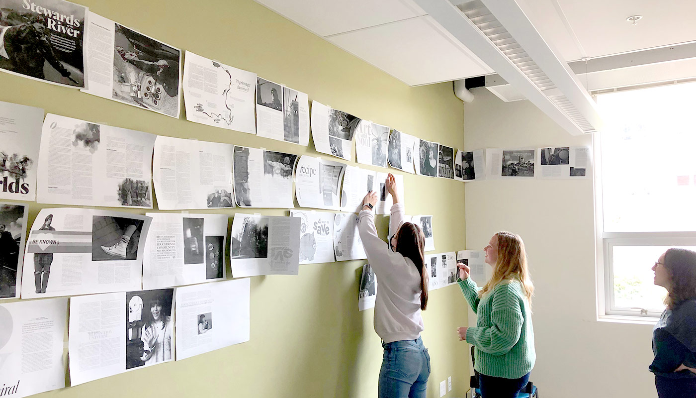 Students hanging pages at magazine wall